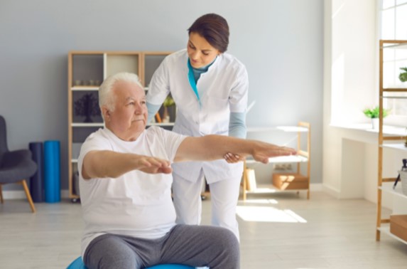 A physical therapist helping her senior patient via balancing exercises